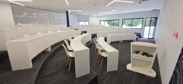 Aula en gradas de ISDI México con escritorios curvos blancos